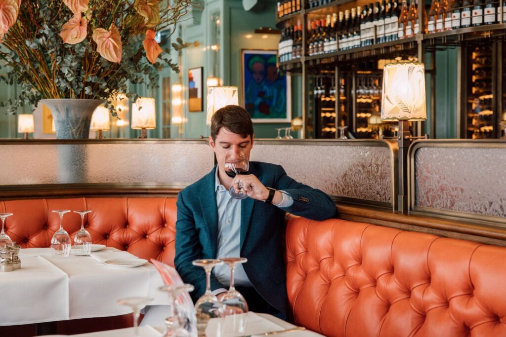 Bild von Marc Almert, CEO Baur au Lac, sitzt im Baur au lac und trinkt Wein.